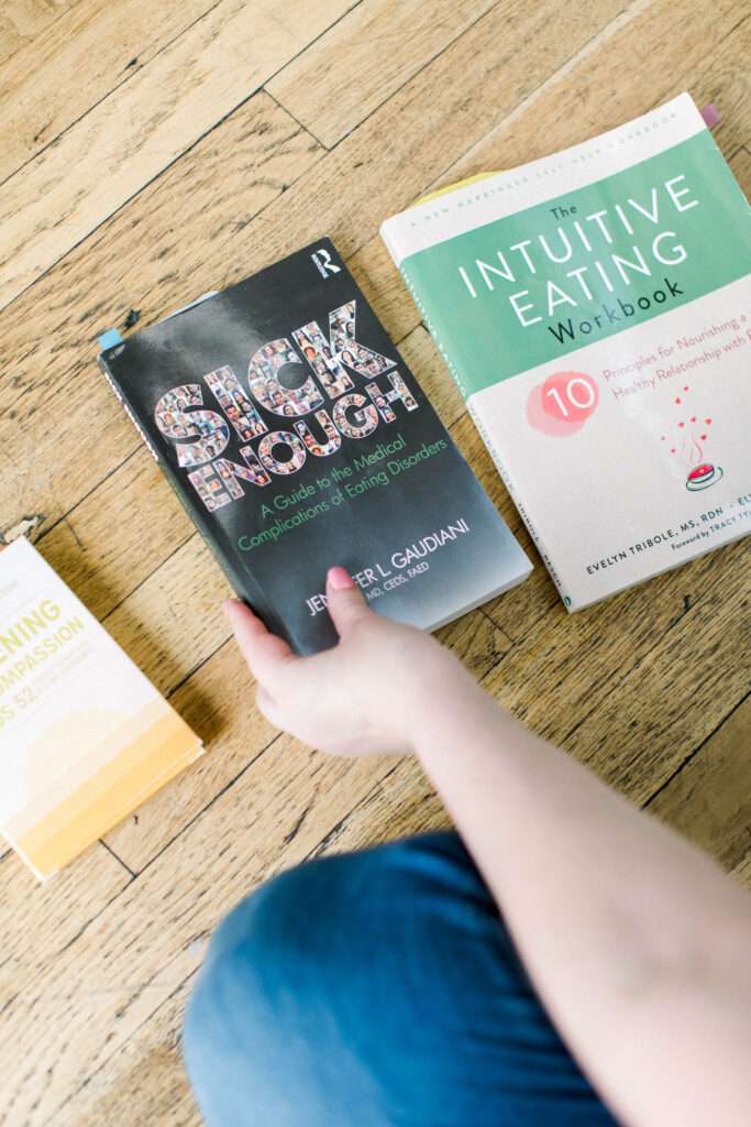 Books for intuitive eating and eating disorder recovery. Sick Enough, Intuitive Eating workbook, and Awakening Self Compassion cards